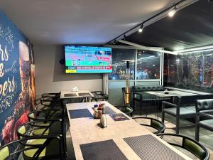 a dining room with tables and chairs and a tv at PMG Hostel in Tirana