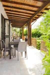 a patio with a table and chairs and a wooden pergola at La Campina de Don Paulu in Galatina