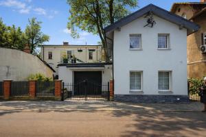 a woman standing in front of a white house at Domek Przy Termach in Jelenia Góra