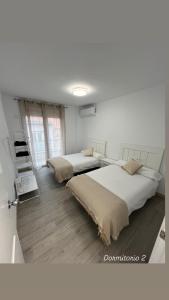 two beds in a white room with twothirdsessionsyss at Piso Moredas in Dúrcal