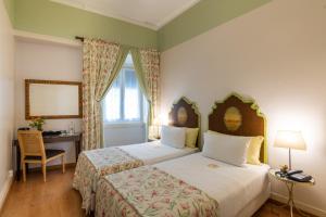 a bedroom with two beds and a desk and a window at Casa de Sao Mamede Hotel in Lisbon