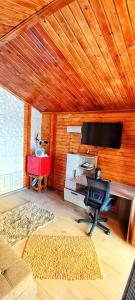 ein Wohnzimmer mit Schreibtisch, Fernseher und Stuhl in der Unterkunft Sunset Oasis in Dătăşeni