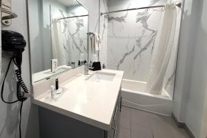 un bagno bianco con lavandino e doccia di Hotel Royale IAH Airport North Houston I-45 a Houston Altre 16 foto