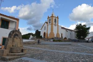 a church with a tower with a clock on it at Pisco Charming House - Alter Pedroso in Alter do Chão