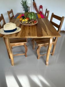 a wooden table with a bowl of fruit and a hat on it at Casa Marion in Puerto Jiménez