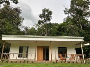 a small white house with chairs on the porch at Casa Marion in Puerto Jiménez
