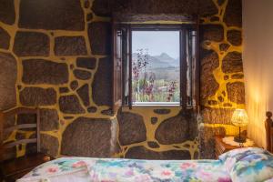 a bedroom with a stone wall with a bed and a window at Casa da Eira in Campo do Gerês