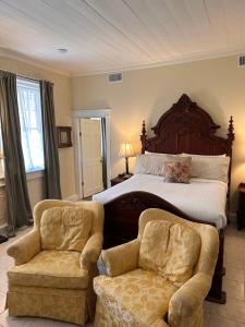 a bedroom with a large bed and two chairs at The Inn at Cedar Grove in Vicksburg