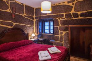 a bedroom with a red bed in a stone wall at Casa da Eira in Campo do Gerês