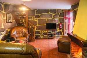 a living room with leather furniture and a stone wall at Casa da Eira in Campo do Gerês