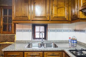 a kitchen with a sink and wooden cabinets at Casa da Eira in Campo do Gerês +38 photos