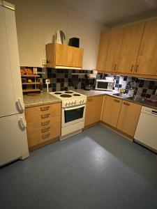 a kitchen with wooden cabinets and a white stove top oven at Central accommodation in Umeå +4 photos