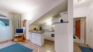 a kitchen with white cabinets and a tv in it at strandnahe FeWo mit Schwimmbad im Haus, a cappella 07, Binz in Binz +20 photos