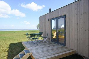 a house with a deck with a table and chairs at Tiny House Pioneer 5 - Green Tiny Spot Schillig in Wangerland
