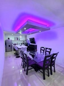 a dining room with purple lighting and a table with chairs at Sweethome Mérida in Mérida