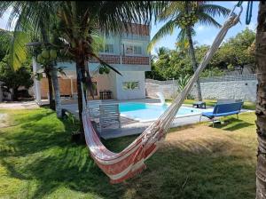 a hammock in front of a house with a pool at Suite Quadrupla Terreo Oceazul in Conde