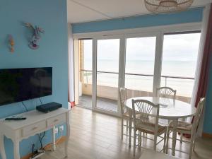 a living room with a dining table and a view of the ocean at Cabourg Face A La Mer in Cabourg