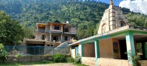 an old building with a tower in front of a mountain at Aashvika Homes in Katrain