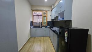 a kitchen with white cabinets and a black refrigerator at Aashvika Homes in Katrain