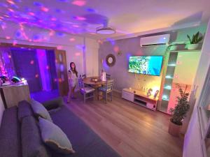 a woman standing in a living room with a table and a tv at Postiguet Beach 2 garajes SuperHost SuperFlat in Alicante