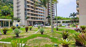 a park in front of a large building with palm trees at Suíte Master Rio de Janeiro Próximo ao Rio Centro 9 Andar! in Rio de Janeiro