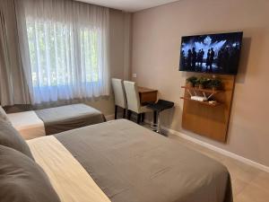 a hotel room with two beds and a flat screen tv at Suite Rincón del Sol 107 in Pinamar