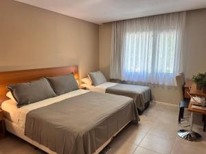 a hotel room with two beds and a window at Suite Rincón del Sol 107 in Pinamar +19 photos