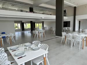 a dining room with white tables and chairs at Suite Rincón del Sol 107 in Pinamar