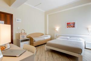 a bedroom with two beds and a desk with a laptop at Hotel Lungomare in Cervia +91 photos