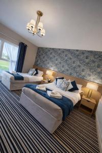 a hotel room with two beds and a chandelier at The Dark Hedges Hotel in Stranocum +77 photos