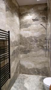 a bathroom with a shower with a stone wall at Nord Boutique Hotel by HORIZONT in Shkodër +126 photos