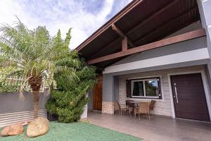 a house with a patio with a table and a palm tree at Casa Atlântida in Xangri-lá