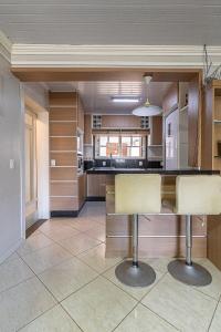 a large kitchen with two bar stools in it at Casa Atlântida in Xangri-lá