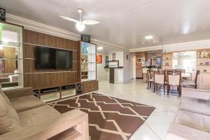 a living room with a television and a dining room at Casa Atlântida in Xangri-lá