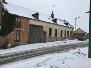 a building with snow on the ground next to a street at Petit AmienSud idéal pour 2 in Saint-Sauflieu