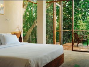 a bedroom with a bed and a large window at vrihee resort in Weligama