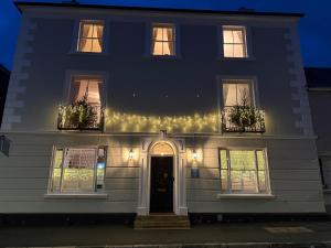a white house with lights on the front of it at Ashburton Court Guest House in Ashburton