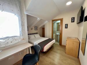 a bedroom with a bed and a chair and a window at Hostal la Colmena in Ávila