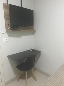 a black desk with a television on a wall at Hotel Moriah in Umuarama