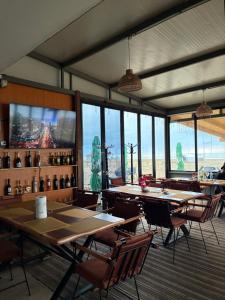 a dining room with tables and chairs and windows at Mango Beach and Hotel in Fier