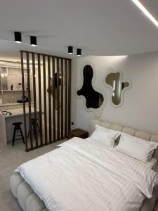 a bedroom with a large white bed with a guitar on the wall at Mediteran Line Apartman 2 in Sombor