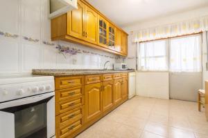 a kitchen with wooden cabinets and white appliances at Private Room in Corroios 15 Minutes from the Beach - Quarto Privado em Corroios com Fácil Acesso à Praia e Lisboa in Corroios