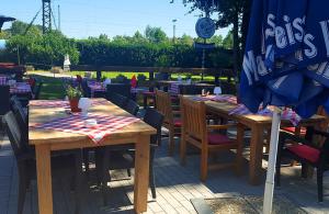 two wooden tables and chairs at an outdoor restaurant at Rooms by Ruhrpadel in Gladbeck