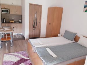 a room with two beds and a table and a kitchen at Kacsó Apartma in Ocna de Sus