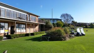a building with a grass yard next to a building at Shearwater Resort in Port Sorell