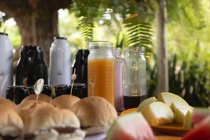 a table topped with plates of food and orange juice at Pousada Mandacaru, próximo a Usina de Arte in Campestre
