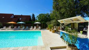 a swimming pool with chairs and umbrellas next to a building at Colors Holiday Hotel in Siófok