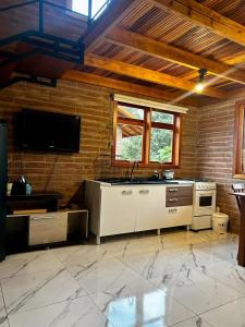 a large room with a kitchen with a tv on the wall at Villetta Gramado Roma in Gramado