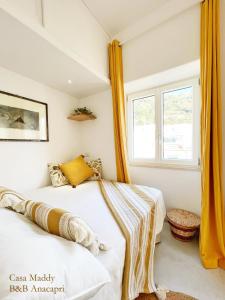 two beds in a room with yellow curtains at Casa Maddy Anacapri Yellow Room in Anacapri