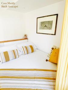 a bedroom with a bed with white sheets and yellow pillows at Casa Maddy Anacapri Yellow Room in Anacapri